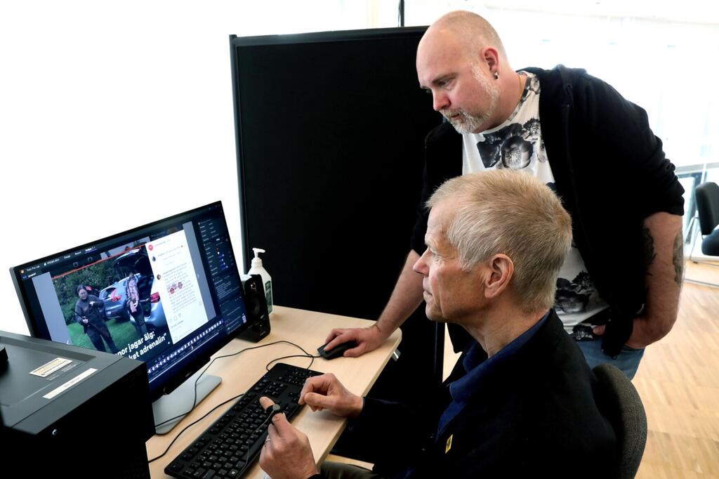 Två män sitter framför en dator och kikar på nyheter.