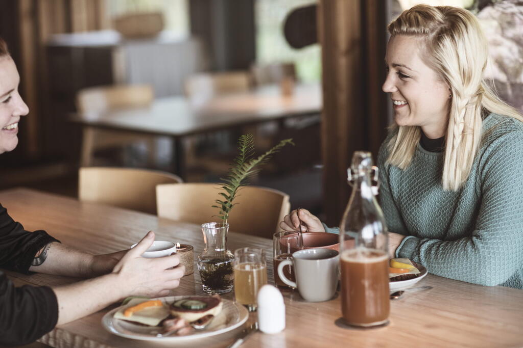Två kvinnor äter frukost och pratar med varandra