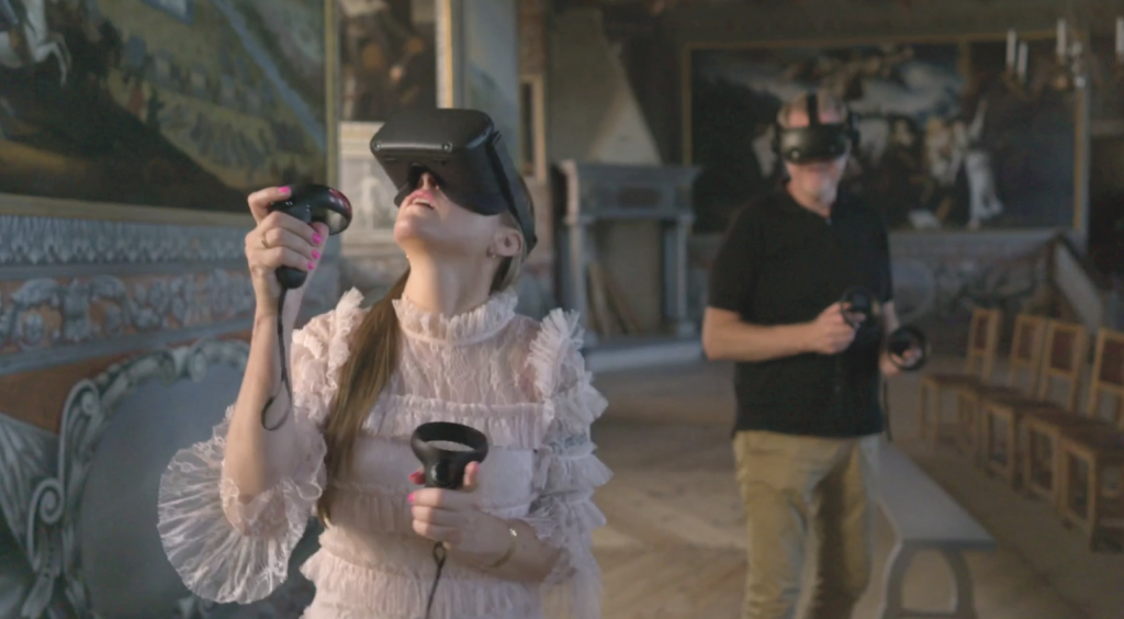 Två personer går runt med VR glasögon på sig bland konstverk 